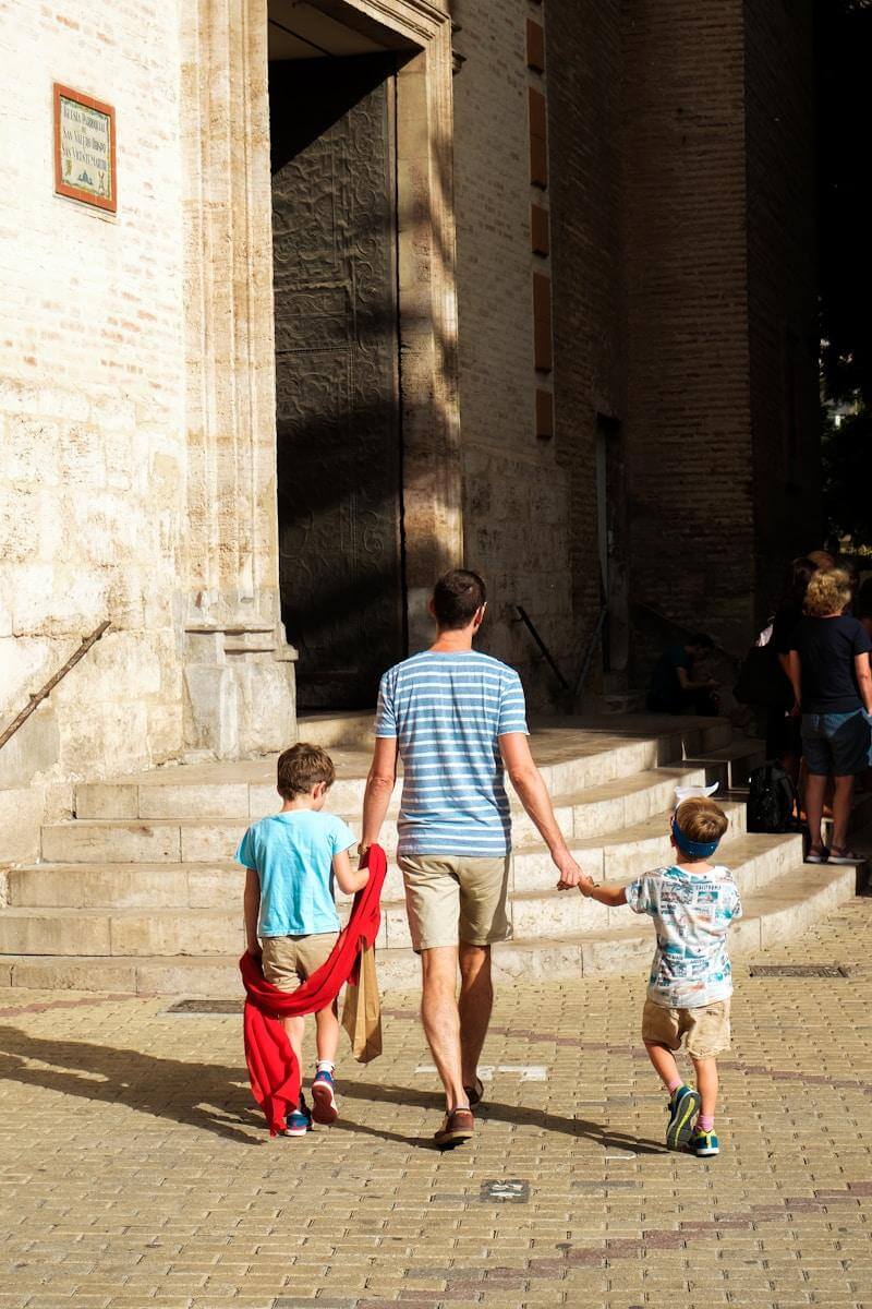 a man and two children are walking down the street to Spanish church